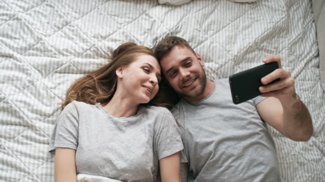 Paar-unter-Selfie-im-Bett-lachen