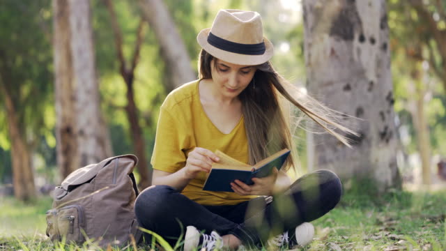 Young-woman-reading-a-book--outdoors