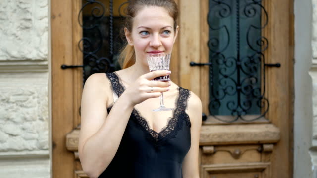 Junge-Frau-trinkt-Wein-aus-einem-Kristallglas-und-genießt-einen-Drink.-Freizeit-von-erfolgreichen-Menschen-auf-der-Straße.