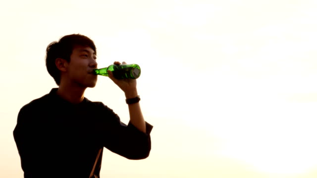 Young-asian-man-drinking-beer-at-rooftop-alone.