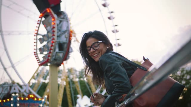 Stilvolle-Mädchen-in-Gläsern-fröhlich-lächelnd-vor-einem-Riesenrad-im-Vergnügungspark