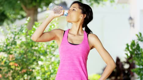 Portrait-ethnic-female-drinking-water-during-exercise-outdoors