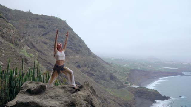 Frau-in-Yoga-Krieger-Pose-auf-den-Ozean,-Strand-und-Felsen-Bergen-meditieren.-Motivation-und-inspirierende-Fit-und-trainieren.-Gesunden-Lebensstil-im-Freien-in-der-Natur,-Fitness-Konzept.