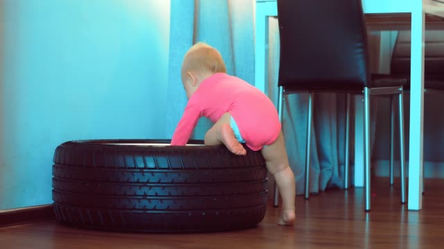 Cute-little-child-touches-and-looks-at-the-car-wheel.-Kid-is-studying-the-car-wheel