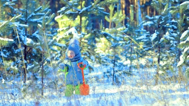 Kind-schüttelt-den-Schnee-vom-Baum.-Kind-hält-einen-Spaten.-Wintertag