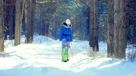 Child-with-his-mother-walks-in-the-winter-forest.-Clear-frosty-day.-Kid-holding-a-spade.-Go-on-the-road