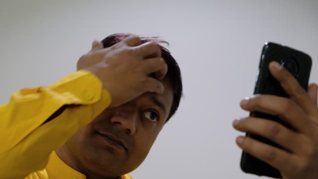 Narzisstische-Mann-mit-Blick-auf-seine-Smartphone-Kamera-auf-sich-selbst-und-machen-und-sein-schwarze-Haar-einstellen