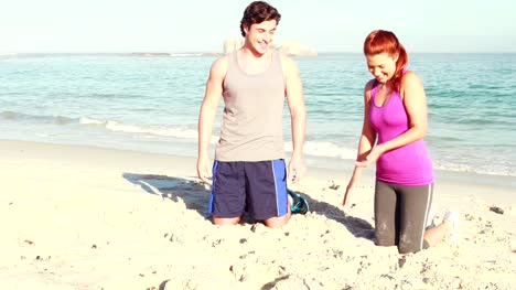 Smiling-couple-doing-push-ups-at-the-beach