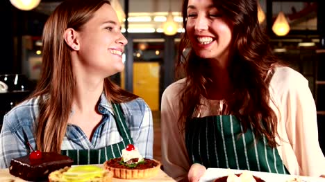 Smiling-waitresses-showing-cakes