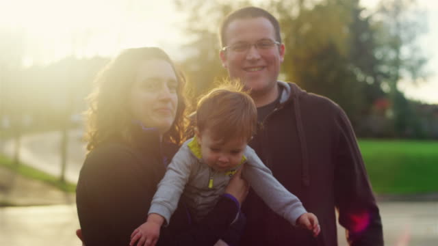 Family-of-three-posing-for-a-photo-with-lens-flare,-little-boy-trying-to-get-away