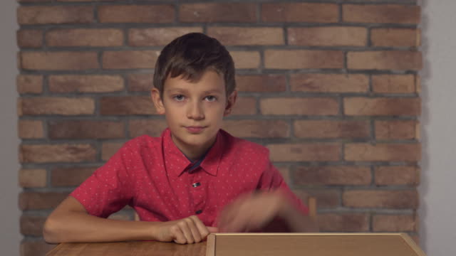 Kind-sitzt-am-Schreibtisch-mit-Flipchart-mit-Schrifttredstrend-auf-der-Rückseite-rote-Backsteinwand