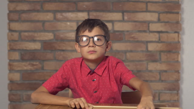 niño-sentado-en-el-escritorio-sosteniendo-rotafolio-con-código-de-letras-en-el-fondo-de-pared-de-ladrillo-rojo
