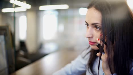 Brunette-woman-in-office-talking-on-telephone-during-break-indoors