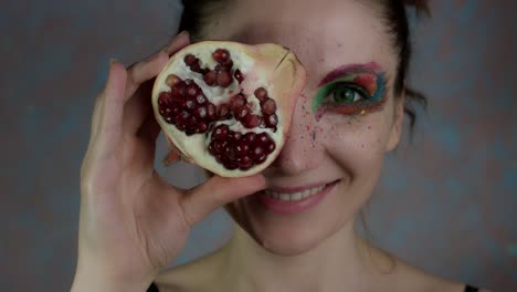 4-k-Aufnahme-einer-Frau-mit-bunten-Make-up-mit-Granatapfel