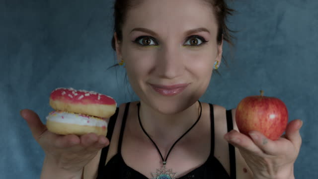 4-k-Aufnahme-einer-Frau-posiert-im-Studio-mit-Donut-und-Apfel