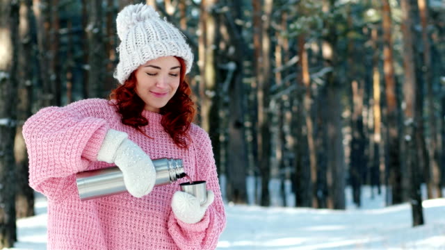 thermos-in-hands-close-up,-hand-in-knitted-gloves-pours-tea-into-a-cup,-woman-pours-hot-drink-from-a-metal-thermos