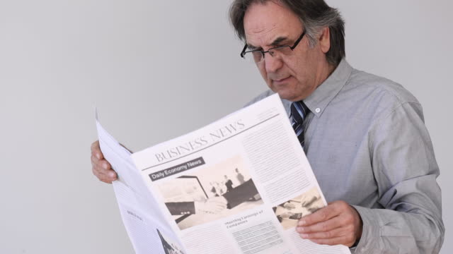 Senior-Mann-lesen-Zeitung-auf-grauem-Hintergrund