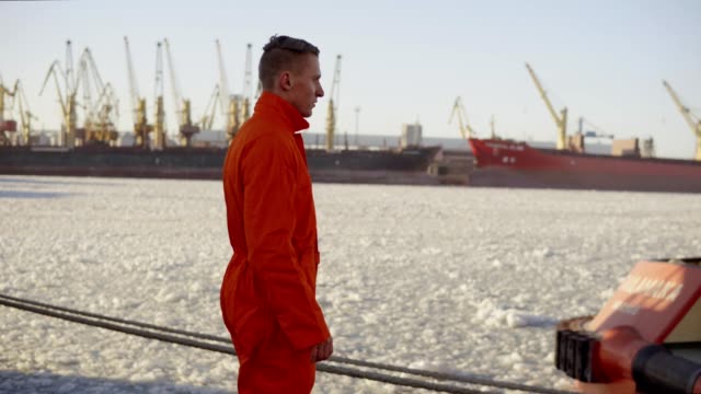 Dock-Arbeiter-in-orange-Uniform-zu-Fuß-in-den-Hafen-und-controlling-Arbeitsprozess-im-Hafen.-Vereisten-See