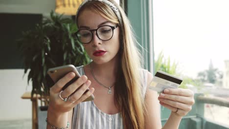 Attraktive-Frau-Einkäufe-mit-Kreditkarte-und-Handy.-Weiblich,-Online-shopping-in-Café.