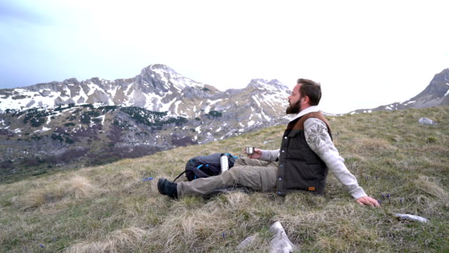 Hiker-sits-and-drinks-hot-tea-from-a-thermos