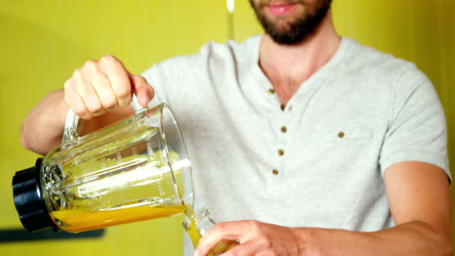 Man-pouring-orange-juice-into-a-bottle