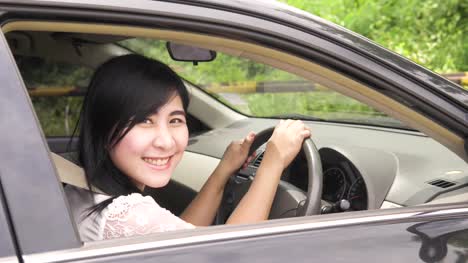 Asian-Portrait-of-young-smiling-woman-sitting-in-the-car