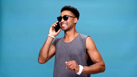 Junge-afrikanische-lächelnder-Mann-reden-am-Telefon-über-blauem-Hintergrund.