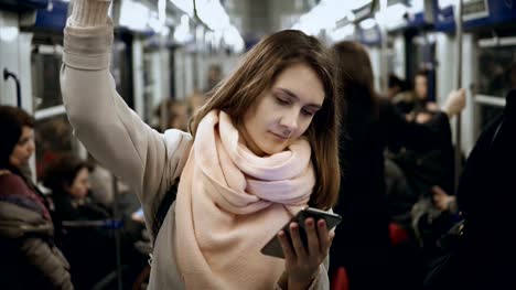 Junge-schöne-Frau-nutzt-das-Smartphone-in-öffentlichen-Verkehrsmitteln,-in-der-u-Bahn.-Mädchen-im-Internet-surfen