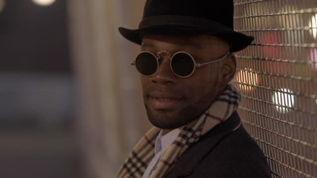 Young-Man-with-African-American-Ethnicity-Wearing-Old-Classic-Look.-Having-Fun-in-the-Big-City-with-Sunglasses,-Hat-and-Scarf.