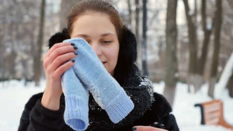 Attractive-woman-blows-at-her-frozen-hands-in-the-winter-park