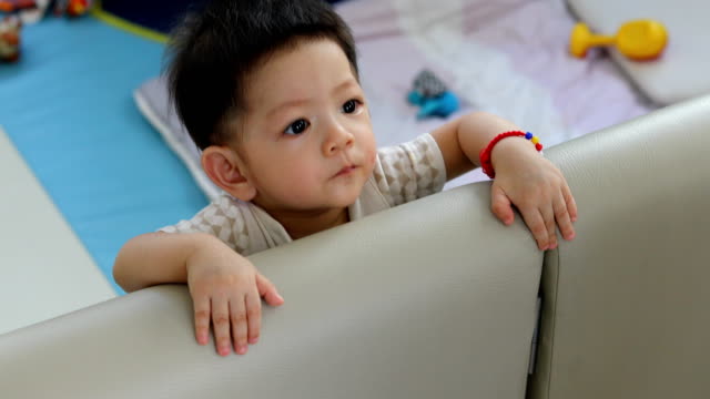 cute-baby-boy-toddler-stand-in-fluffy-mattress-partition-in-limit-area-self-protection