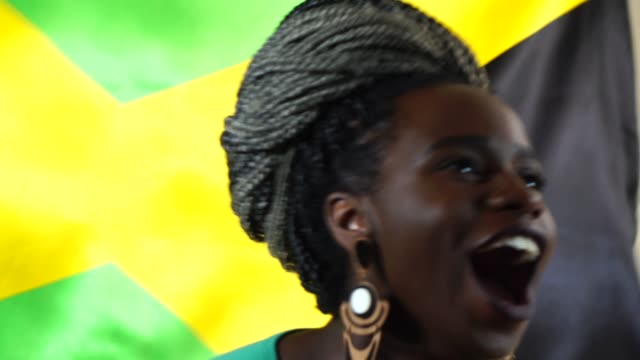 Jamaikanische-junge-schwarze-Frau-feiert-mit-Jamaika-Flagge