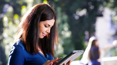 Beautiful-asian-woman-in-a-park-uses-the-tablet
