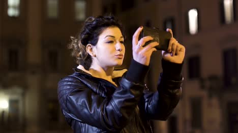 Charming-brunette-shoots-funny-selfie,-city-nights-in-the-background