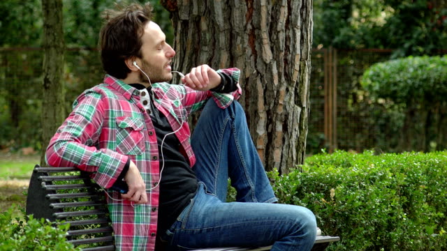 relaxed-man-in-the-park,-talking-on-the-phone-with-earphones