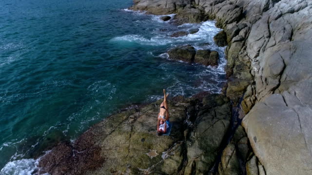 Aerial:-Acro-Yoga-on-the-rocks-near-the-sea-and-beautiful-waves.