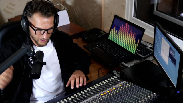 DJ-Kopfhörer-neben-Mischpult-sitzen-und-am-Computer-Kontrastblenden-in-Mike-sagt