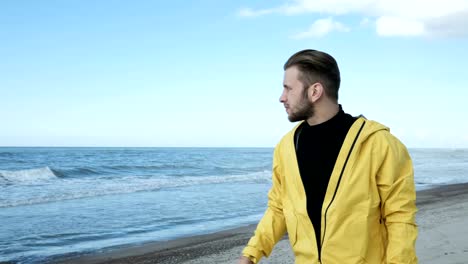 Hipster-in-Regenmantel-zu-Fuß-am-Strand-allein