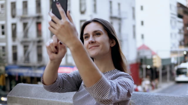 Junge-schöne-Frau-Selfie-fotografieren-auf-Smartphone.-Befahrenen-Straße-und-beschäftigt-Stadtbild-auf-dem-Hintergrund