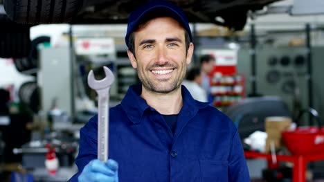 Portrait-of-a-young-beautiful-car-mechanic-in-a-car-workshop,-in-the-background-of-service.-Concept:-repair-of-machines,-fault-diagnosis,-repair-specialist,-technical-maintenance-and-on-board-computer