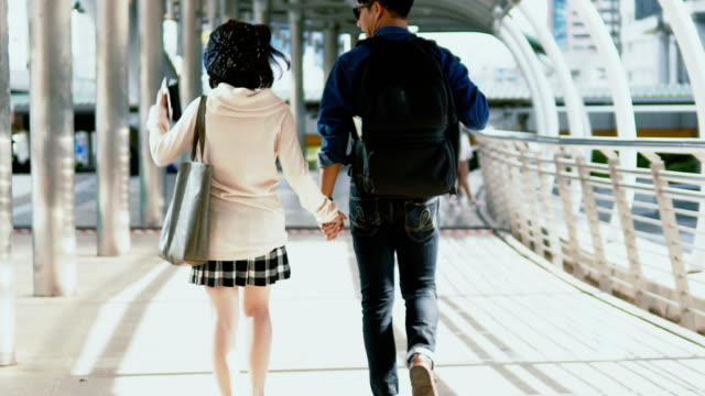 Behind-young-couple-holding-hands-and-walking-together