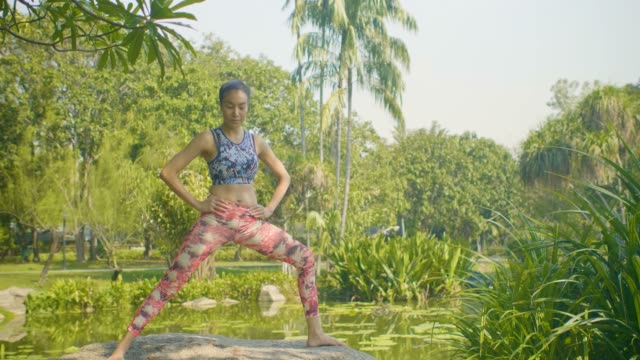 Junge-asiatische-Frau-Yoga-außerhalb-mit-schönen-Sonnenstrahlen-im-Park-machen.