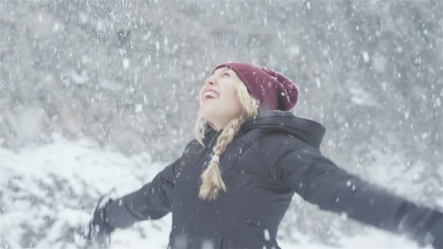 Beautiful-young-Asian-woman-throwing-snow-in-the-air-on-a-forest
