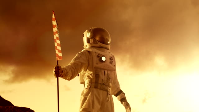 Astronaut-Raumanzug-tragen-Pflanzen-amerikanische-Flagge-auf-dem-roten-Planeten-/-Mars,-sieht-den-Horizont.-Patriotische-und-stolzer-Moment-für-die-ganze-Menschheit.-Raumfahrt-und-Kolonisierung-Konzept.