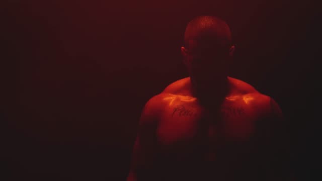 Muscular-black-man-standing-on-a-foggy-dark-red-background