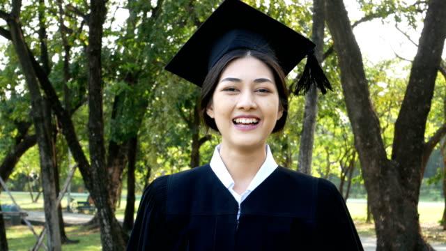 Young-Asian-Woman-Students-wearing-Graduation-hat-and-gown,-Garden-background,-Woman-with-Graduation-Concept.