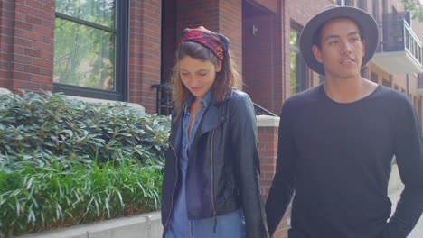 A-hipster-couple-walking-down-the-sidewalk-holding-hands