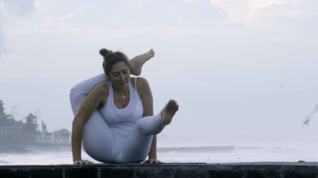 Frau-praktizieren-Yoga-am-Pier