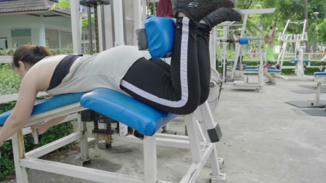 Asian-woman-pushing-weight-equipment-by-leg