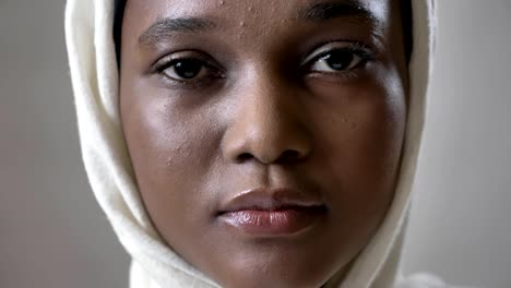Ofoung-cara-triste-niña-musulmana-africana-en-hijab-es-mira-hacia-arriba-y-mirando-a-cámara,-religioun-concepto,-fondo-gris